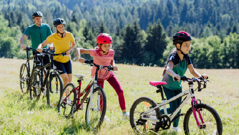 imagem com familia com dois filhos a andar de bicicleta a representar a segurança das crianças nas férias